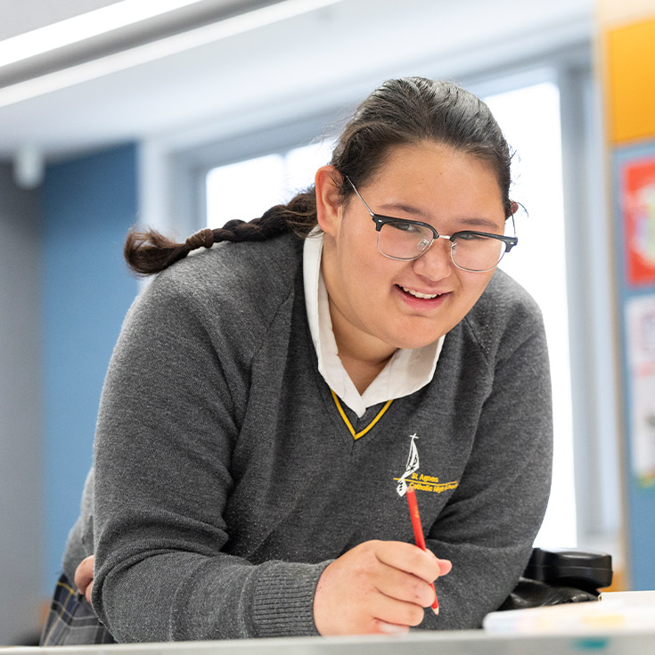 Student writing at her desk in the classroom at St Agnes Catholic High School Rooty Hill